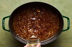 wine being poured into a pot with butter, nutmeg, thyme, bay leaf, garlic, salt, pepper and caramelized onions