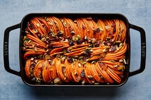 healthy sweet potato casserole topped with pumpkin seeds, candied ginger, dried cranberries & chopped pecans