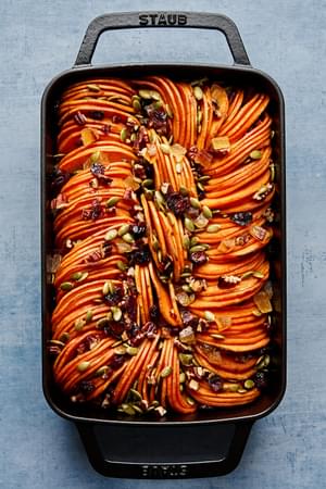 healthy sweet potato casserole topped with pumpkin seeds, candied ginger, dried cranberries & chopped pecans