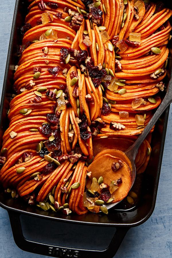 healthy sweet potato casserole topped with pumpkin seeds, candied ginger, dried cranberries & chopped pecans