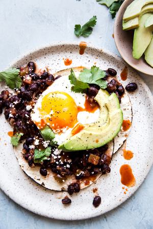 Huevos rancheros on a plate with beans ann egg and avocado