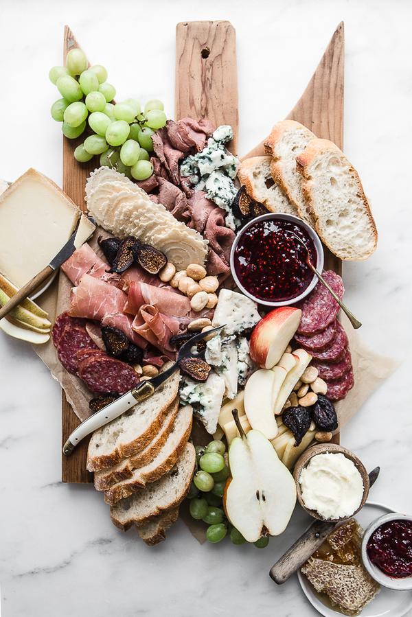 Cheese charcuterie board with grapes, apples, honey, nuts and bread