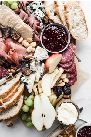 Cheese charcuterie board with grapes, apples, honey, nuts and bread
