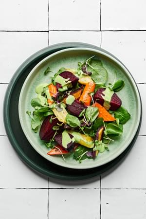 Roasted beet salad made with beets, carrots, spring salad mix and micro greens drizzled with green goddess dressing