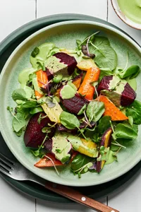 Roasted beet salad made with beets, carrots, spring salad mix and micro greens drizzled with green goddess dressing
