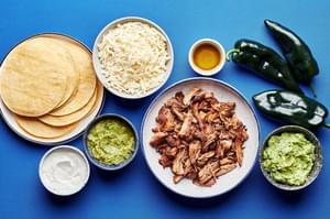 corn tortillas, mozzarella, carnitas, poblano peppers, olive oil, sour cream, guacamole and salsa verde in prep bowls