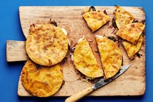 carnitas quesadillas with roasted carnitas being sliced on a cutting board