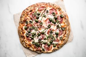 Salami, Jalapeño & Olive Pizza with Honey on parchment