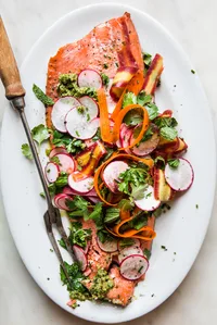 Roasted Salmon With Spring Pesto on a platter with radishes, mint, cilantro and carrot ribbons