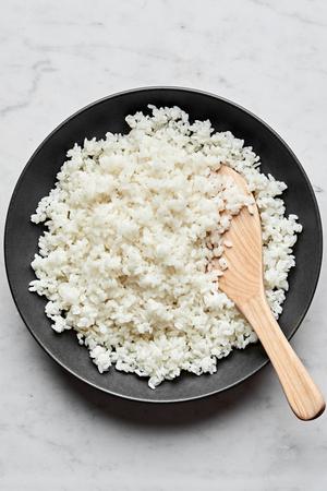 homemade sushi rice made with salt, sugar and unseasoned rice vinegar in a serving bowl with a wooden spoon
