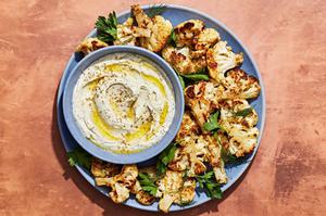 za'atar roasted cauliflower on a serving platter with a bowl of herb whipped feta