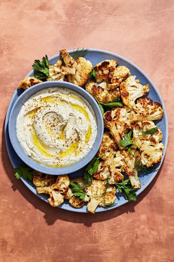 za'atar roasted cauliflower on a serving platter with a bowl of herb whipped feta