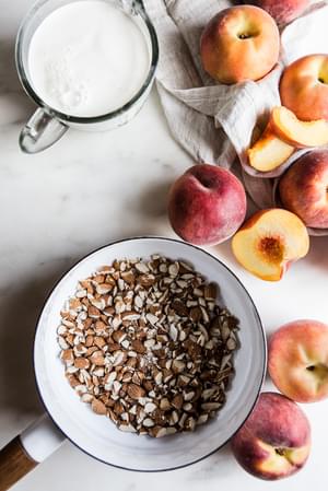 whole milk, heavy cream in a pot, next to peaches, and almonds