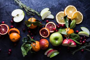 apples, oranges, cranberries and rosemary on the counter