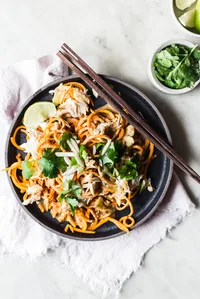 Pad Thai made with sweet potato noodles with cilantro and lime on a plate
