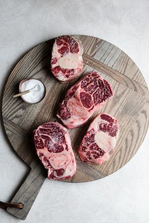 raw osso buco, cross cut beef shanks on a cutting board with salt