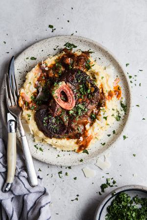 homemade osso buco cross cut beef shanks with sauce on a plate with mashed potatoes
