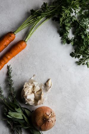 carrots, garlic, onions, thyme and herbs on a counter