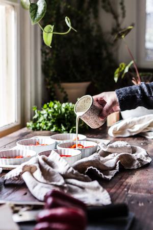 hand pouring cream into ramekin for baked eggs