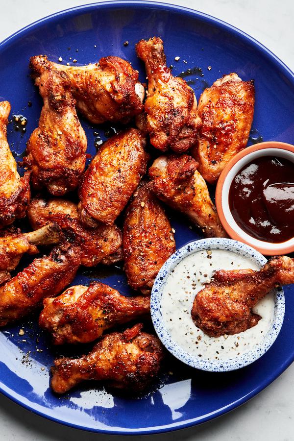 Homemade baked chicken wings on a plate served with ranch dressing and bbq sauce in small bowls