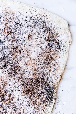 ground coffee, cinnamon and sugar sprinkled on to butter on dough