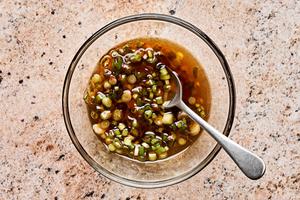 sesame oil, chili paste, and scallions being stirred together in a bowl