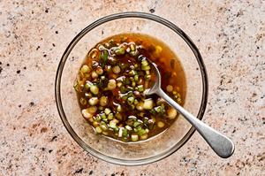 sesame oil, chili paste, and scallions being stirred together in a bowl