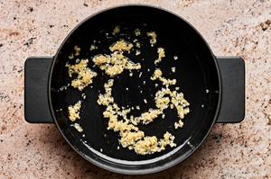 ginger and garlic being cooked in a soup pot with sesame oil