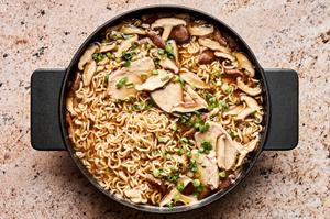 a pot of easy chicken ramen soup made with ginger, soy sauce, green onions and mushrooms