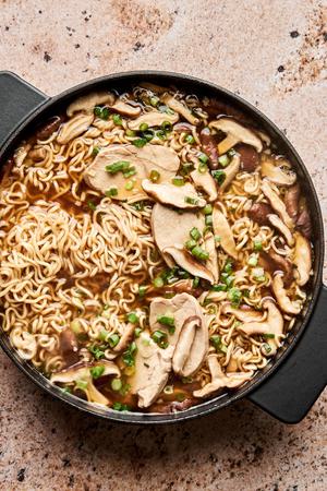 a pot of easy chicken ramen soup made with ginger, soy sauce, green onions and mushrooms