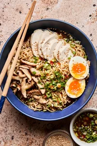 a bowl of easy chicken ramen soup topped with Scallion Chili Sesame Oil, sesame seeds and a halved boiled egg
