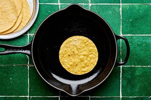 corn tortillas being cooked in a skillet in olive oil
