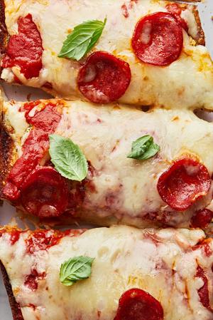 homemade french bread pizza cut into slices made with marinara, cheese, pepperoni and fresh basil