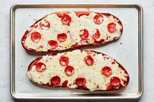 homemade french bread pizza on a baking sheet just out of the oven made with marinara, cheese and pepperoni
