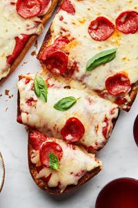 homemade french bread pizza cut into slices made with marinara, cheese, pepperoni and fresh basil