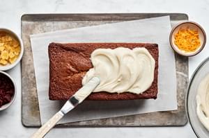 gingerbread loaf spiced with cinnamon, cloves and ginger being frosted with cream cheese frosting