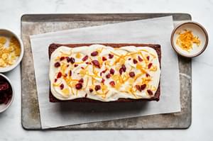 gingerbread loaf topped with cream cheese frosting, candied ginger, orange zest and dried cranberries