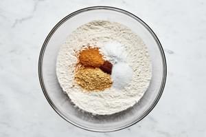 flour, baking soda, salt, cinnamon, cloves and ginger being combined in a bowl