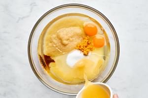 eggs, sugar, applesauce, vegetable oil, vanilla, orange zest, and orange juice being combined in a bowl