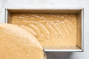 gingerbread batter spiced with cinnamon, cloves and ginger being poured into a greased 9x5 metal baking pan