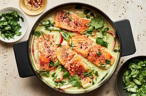 homemade green curry salmon in a large pot made with coconut milk, lime juice, ginger, fish sauce, peppers and onions