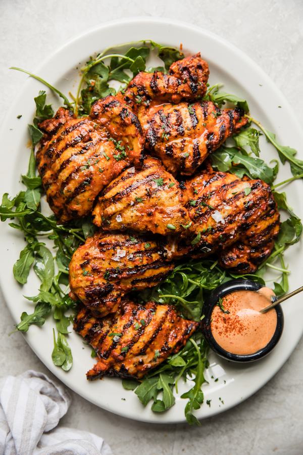 Grilled harissa chicken on a plate with arugula
