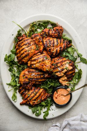 grilled harissa chicken on a plate with arugula and harissa mayonnaise
