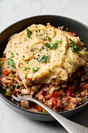 healthy shepherd's pie in a bowl made with ground beef, onion, carrots, cabbage topped with mashed parsnips