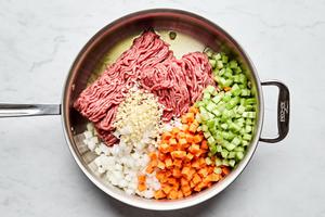 beef, onion, carrots, celery, and garlic cooking in a skillet