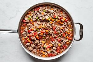 healthy shepherd's pie filling being cooked in a skillet made with beef, onion, carrots, celery, and garlic