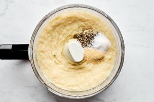 boiled parsnips being mashed with chicken stock, salt, pepper and garlic in a food processor