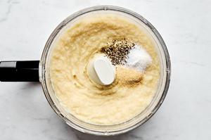 boiled parsnips being mashed with chicken stock, salt, pepper and garlic in a food processor