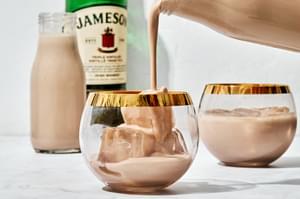 homemade Irish cream liqueur being poured into a cocktail glass over ice