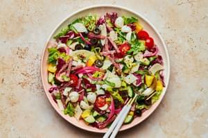 Italian Chopped Salad with homemade Italian salad dressing in a serving bowl with serving spoons on the counter